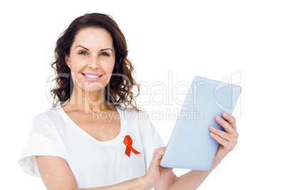 Woman with red aids awareness ribbon using tablet