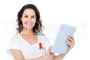 Woman with red aids awareness ribbon using tablet