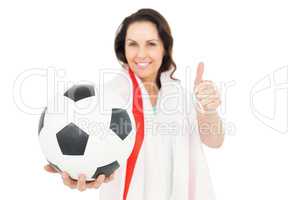 Pretty brunette with thumbs up holding soccer ball