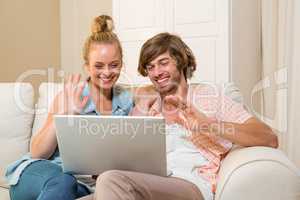 Cute couple using laptop sitting on the couch