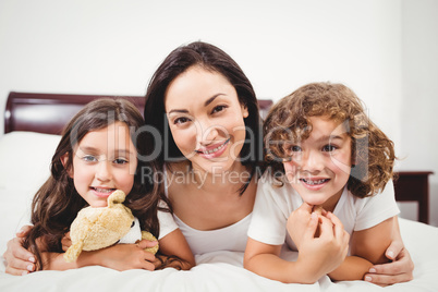 Happy woman with children lying on bed at home