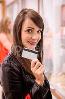 Portrait of beautiful woman showing her credit card in a jeweler