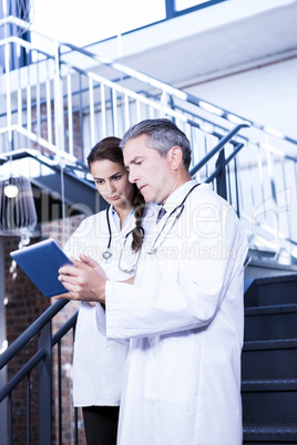 Doctors using digital tablet on staircase