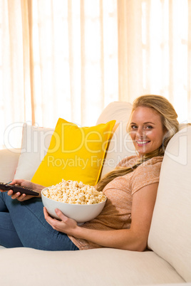 Pretty blonde watching TV and eating pop corn