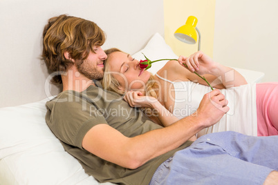 Cute couple cuddling with girlfriend smelling a rose