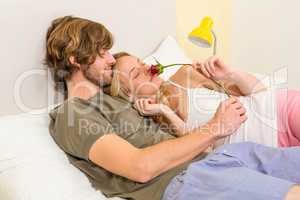 Cute couple cuddling with girlfriend smelling a rose