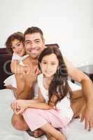 Happy father with daughter and son on bed at home