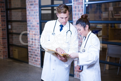 Two doctors looking at file and discussing near library