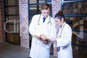 Two doctors looking at file and discussing near library