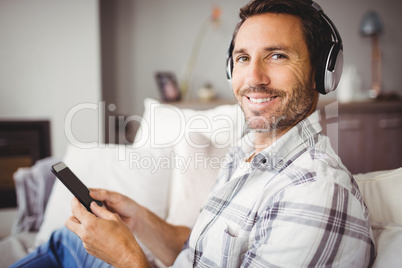 Portrait of man wearing headphones while using mobile phone