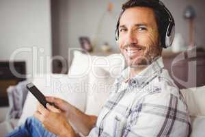 Portrait of man wearing headphones while using mobile phone
