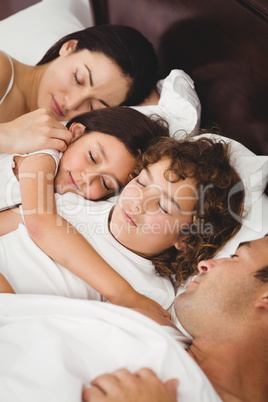 Children sleeping with parents on bed