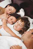 Children sleeping with parents on bed