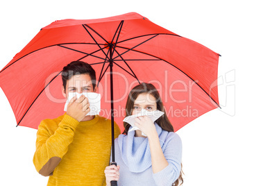 Couple blowing their noses under an umbrella