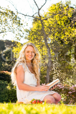 Beautiful blonde sitting on the grass reading