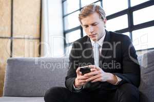 Businessman text messaging on mobile phone