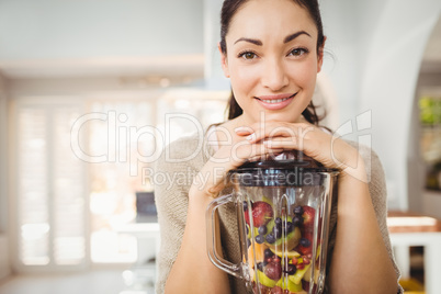 Portrait of happy woman preparing fruit juice