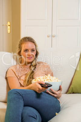 Pretty blonde watching TV and eating pop corn