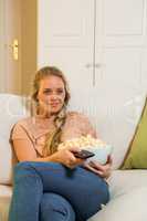 Pretty blonde watching TV and eating pop corn
