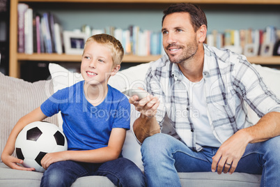 Smiling father and son watching football match