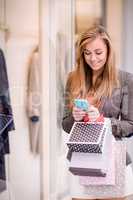 Beautiful woman using her phone while window shopping