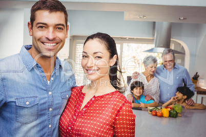 Portrait of happy couple with family preparing food in backgroun Portrait of happy couple with family preparing food in backgroun