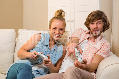 Cute couple playing video games sitting on the couch