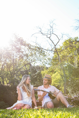 Happy couple having a picnic and playing guitar