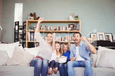 Happy family with arms raised while watching television