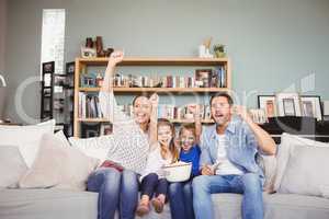 Happy family with arms raised while watching television