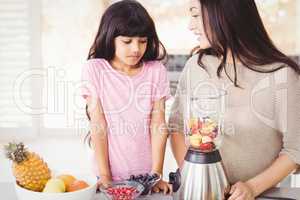 Happy mother and daughter preparing fruit juice