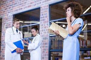 Female doctor thinking while checking a file near library