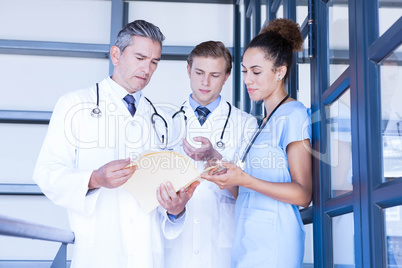 Doctors discussing medical report in corridor