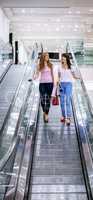 Two beautiful women on escalator of shopping mall