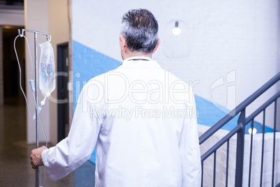 Male doctor carrying saline stand