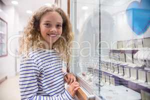 Portrait of happy girl standing near jewelry display