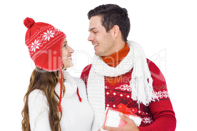 Happy couple with winter clothes holding gift box