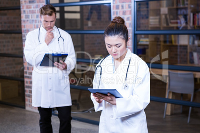 Female doctor using digital tablet near library