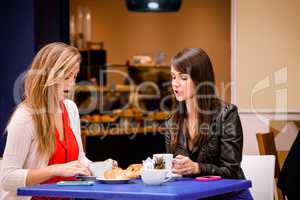 Women talking while having coffee and snacks at a coffee shop