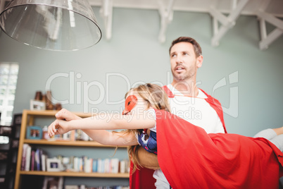 Father holding daughter with superhero costume