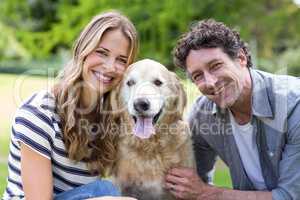 Smiling couple with dog in the park