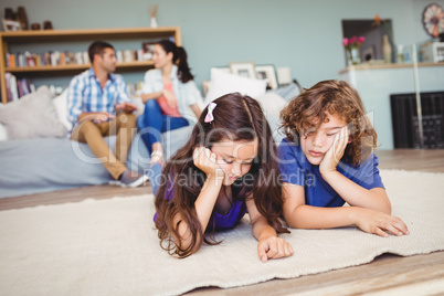 Children resting on carpet while parents in background