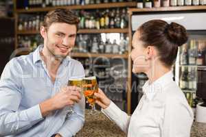 Man and barmaid toasting with beers