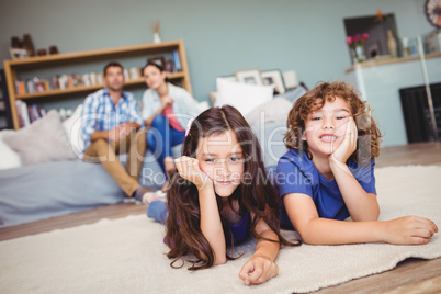 Children resting on carpet while parents sitting in background
