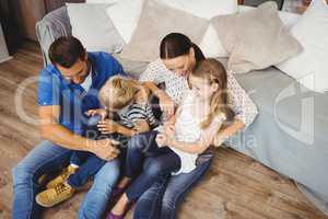 High angle view of happy family sitting by sofa