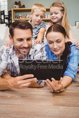 Parents with digital tablet while children sitting on their back