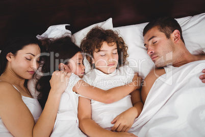 High angle view of children sleeping with parents on bed