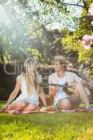 Happy couple having a picnic and playing guitar