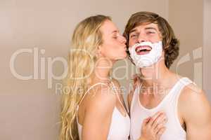 Blonde kissing her boyfriend with shaving foam on the face