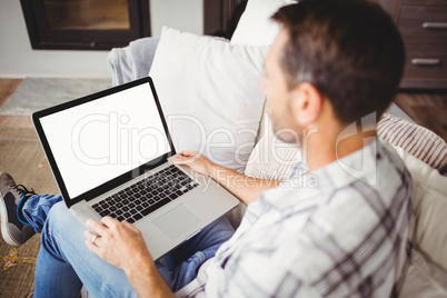 Man using laptop while sitting on sofa at home